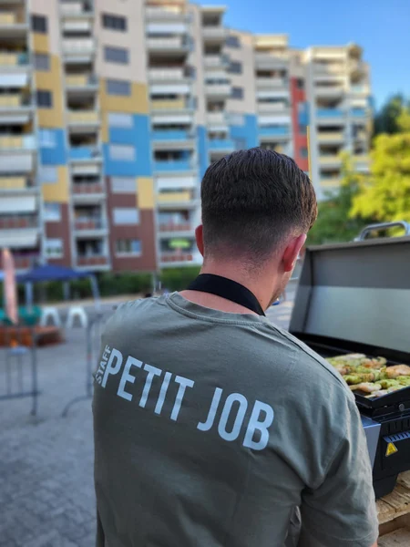 Un jeune portant un t-shirt Petit Job devant les immeubles des Avanchets, rapport 2025