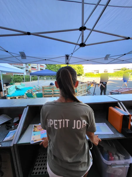 Un jeune portant un t-shirt Petit Job participe à une buvette, rapport 2025